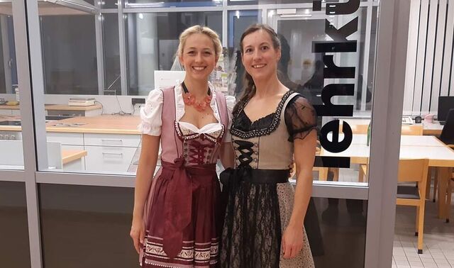 Die beiden Ernährungsberaterinnen tragen einen Dirndl und stehen einladend vor der Lehrküche.