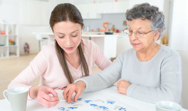 Die Grafik zeigt eine von Demenz betroffene Frau mit einer Angehörigen beim Trainieren des Gedächtnisses durch Puzzeln.