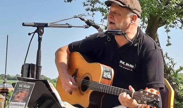 Dr. Mojo singt mit seiner Gitarre im Freien