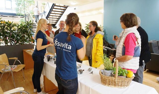 Zwei Ernährungsberaterinnen der savita stehen an ihrem Stand. Davor sind eine Reihe Besucherinnen zu sehen, die an den Duftproben schnuppern.